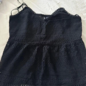 Svart spetslinne - Snyggt svart spetslinne med smala axelband och vacker spetsdetaljering. Perfekt för en stilren look.