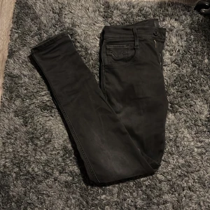 Svarta jeans från Replay - Snygga svarta jeans från Replay i modellen Anbass. De har en slim passform och är tillverkade i ett stretchigt material för extra komfort. Perfekta för en stilren look med klassiska fem fickor och dragkedja.