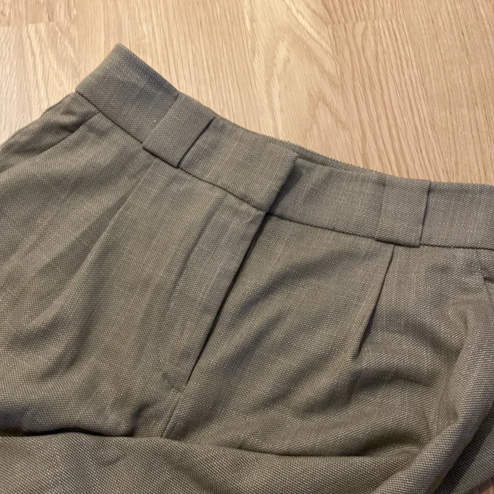 Säljer ett par stilrena beige kostymbyxor i storlek 34. De är högmidjade och har en rak passform som ger en klassisk look. Perfekta för både kontoret och mer formella tillfällen. Byxorna har diskreta fickor baktill och är i ett bekvämt material som känns skönt mot huden.. Jeans & Byxor.