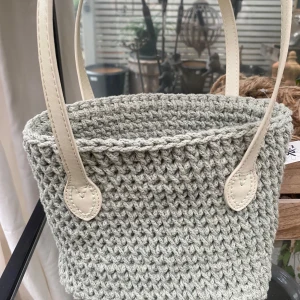 Stickad beige väska - Säljer en superfin virkad beige väska med snygga detaljer. Den har två rejäla handtag och en stabil botten med små metallfötter. Perfekt för vår och sommar!
