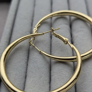 Guldiga hoop-örhängen - Stora, glänsande guldiga hoop-örhängen. Örhängena är i nyskick och har har aldrig använt . postar inom tre dagar efter köpet 