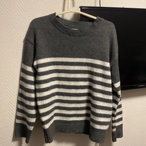 Grå stickad tröja  - Jätteskön stickad tröja med vita ränder i storlek M (38). Passar jättebra nu när det börjar bli kyligt ute! 