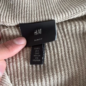 Beige slim fit tröja från H&M - Säljer en snygg beige slim fit tröja från H&M. Den är ribbad och har en dragkedja framtill som ger en stilren look. Perfekt för både vardag och lite finare tillfällen. Passar bra till höst och vår!