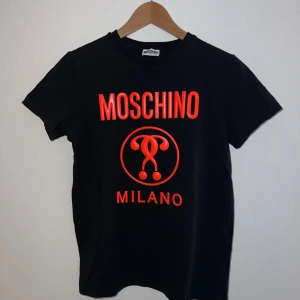 Moschino Milano T-shirt strl. S - En Moschino T-shirt i strl. S,mycket bra skick, använd fåtal gånger. Säljer pga rensning. Köparen står för frakten. För att köpa, kontakta mig eller köp via ”köp nu”. Katt finns i huset. 