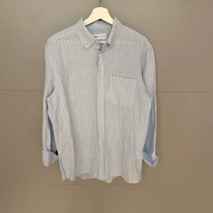 Ljusblå randig skjorta från Zara - Säljer en stilren ljusblå skjorta från Zara. Den är randig och har en klassisk krage med knappar. Skjortan är långärmad och har en bröstficka. Perfekt för både vardag och fest!
