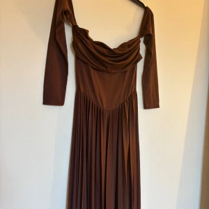 Kort balklänning  - En mörkbrun , kort balklänning i i storlek 36. Off shoulder men kan även hade på axlarna om man vill . Aldrig använd, utan helt ny .