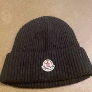 Moncler mössa  - Svart Monclermössa i gott skick men knappt spår på användning. Säljs med påse och tagg. Pris diskterbart. Mer info i pm!