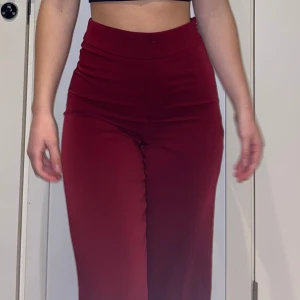 Röda kostymbyxor  - Röda vida kostymbyxor från Bik Bok. Storlek 34. Knappt använda så väldigt fint skick men används aldrig. Jätteskönt material med dragkedja på sidan. 