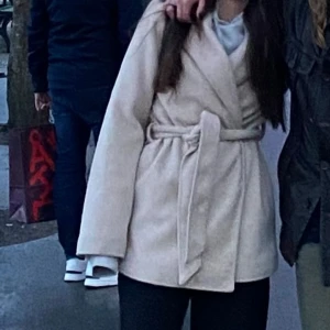 Beige kappa - Beige kappa i storlek S. Ett hål i ena fickan 