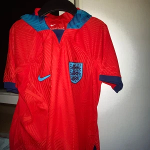 England fotbolls tröja  - Säljer en England fotbollströja i storlek S, i perfekt skick (10/10). Jag har endast haft den på mig ca 7-9 gånger, och därefter har den legat i garderoben. Inga skador, fläckar eller slitage