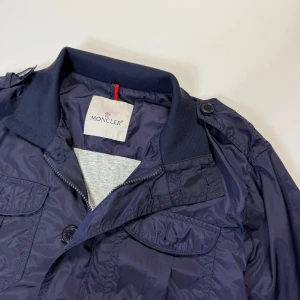 MONCLER WINDBREAKER  - Moncler Windbreaker  Storlek:4 passar m Skick:8/10 Moncler patchen  saknas samt en knapp, finns små märken på jackan på baksidan och på armarna Vid frågor eller funderingar skicka ett pm