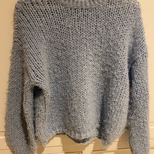 Ljusblå stickad tröja från Vero Moda - Mysig ljusblå stickad tröja från Vero Moda. Perfekt för kyliga dagar med sin fluffiga och mjuka textur. Tröjan har en avslappnad passform och långa ärmar, eftersom materialet är lite fluffigt så har det ”gluggar ihop” lite 😂 ( se bilderna) annars bra skick 💙
