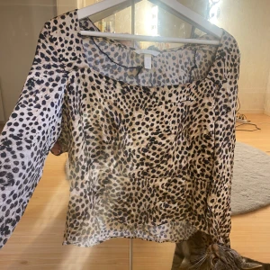 Leopardmönstrad blus - Säljer en snygg leopardmönstrad blus i storlek M. Blusen har långa ärmar och är perfekt för både vardag och fest. Materialet är lätt och luftigt, vilket gör den bekväm att bära. 