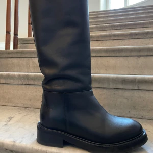 Svarta modestövlar - Snygga stövlar i kalvläder med rakt skaft från märket Flattered. Storlek 35 men rymliga  Skaftlängd: 39 cm Skaftomkrets: 40 cm Nypris: 4195kr