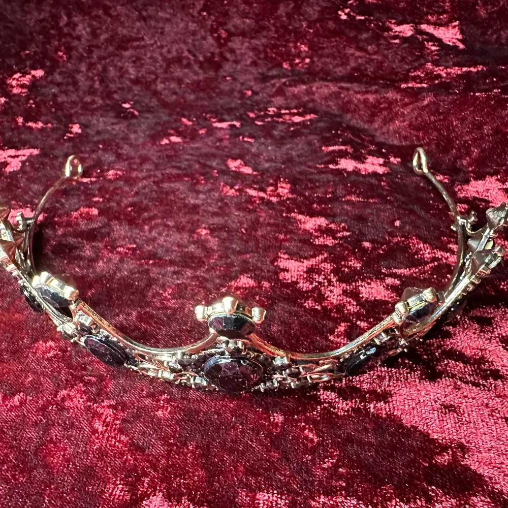 En krona / tiara värdig en vampyrdrottning, mörkeralv eller gothprinsessa. Vacker och välgjord med glittrande svarta stenar & strass mot mörkt guldfärgad ram. Bredd 14,5 cm, båglängd 32 cm, höjd längst fram 5 cm.  Gediget gjord, bekväm att bära. . Accessoarer.