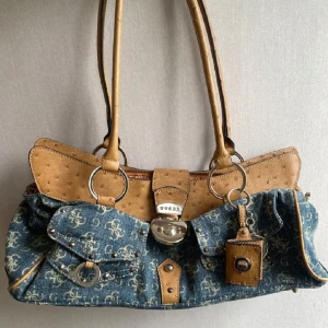 Vintage Guess väska  - I denim material, finns flera innerfack och ytterfack. Vintage och går ej att få tag i längre. Pm för mer info! Priset går att diskutera💞