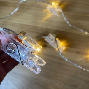 Ljusslinga med klämmor - ljusslinga med klämmor för att hänga bilder eller nåt annat. 12 st lampor med klämmor, dock har en klämma försvunnit (se bild). Klämmorna går att ta av och på.  Hör av dig om du har frågor🩵