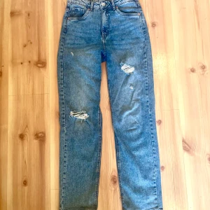 Blå jeans från LAB Industries - Säljer ett par snygga blå jeans från LAB Industries. De har en cool distressed look med slitningar på framsidan. Jeansen är midwaist och har en straight passform, perfekt för en avslappnad stil. De är i bra skick och redo för en ny ägare!