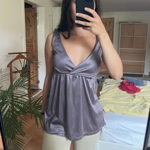 Metallisk topp - Söt vringad topp i ett metalliskt tyg. Står stl m men jag anser att den passar bäst stl S. Bredare axelband och smickrande modell! 