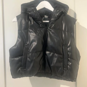 Svart väst i skinn imitation  - Supersnygg lite kortare väst i svart skinn imitation, använda ca 3 gånger så den är som ny, inga skador! Är i en storlek S men modellen är lite lösare o kortare😊