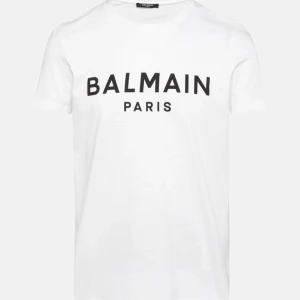 Vit och svart t-shirt från Balmain - Säljer två snygga t-shirts från Balmain i klassiska färger. Den ena är vit med svart text och den andra är svart med vit text. Båda har korta ärmar och är gjorda i mjuk bomull. Perfekta för en stilren look!