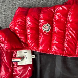 Moncler väst  - Hej  Säljer nu  min unika röda  moncler väst då den är lite förstor för mig den är lite sliten som ni kan se på två av bilderna men skulle säga att skick 6-10 billigare vid snabb affär är gärna öppen för byten 
