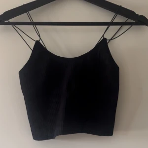 Kort ribbad topp BikBok  - Svart tight topp ifrån BikBok. Kortare, ribbad med tunna axelband. Aldrig använd. Storlek XS/S. Normal i storleken. 