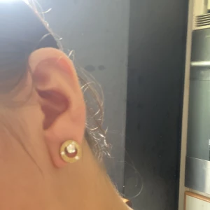 Guldörhängen från Guess med kristaller - Säljer ett par snygga guldörhängen från Guess. De har en rund design med glittrande kristaller i mitten och runt om. Perfekta för att ge en touch av glamour till vilken outfit som helst. Kommer med originalpåse och certifikat.