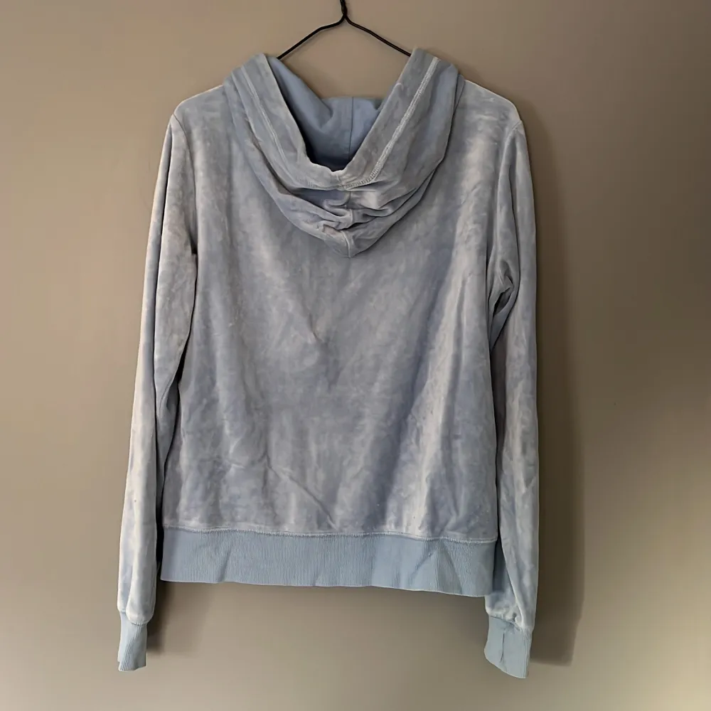 Blå hoodie i materialet velour, med dragkedja. Storlek L. Hupparit & Collegepaidat.