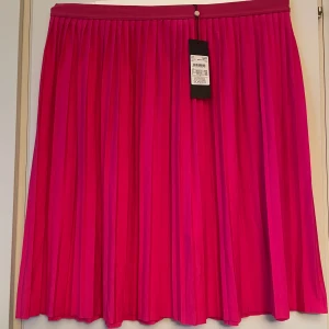 *NY*Kjol i stl XL Fr Soaked in Luxury - En plisserad kjol i midi längd från Soakedin Luxury, i mörkare cerise, superfin färg! Stl XL, normal i storleken.  Kjolen har en elastisk midja och är i A-linjeform. Den är perfekt för både vardag och fest!  Inget att anmärka på. Ord pris 399, nu 110