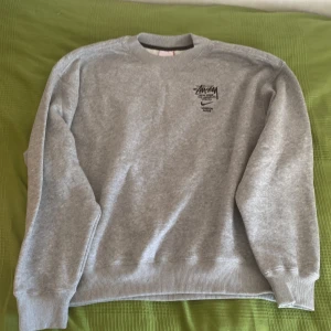 Grå sweatshirt från Nike x Stüssy - Säljer en snygg grå sweatshirt från Nike i samarbete med Stüssy. Använd ett fåtal gånger men säljer den då den var lite lång i ärmarna för min smak.