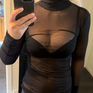 Meshtopp ifrån GinaTricot  - Genomskinlig, svart mesh-topp med halvpolo ifrån GinaTricot. Lappen är ej kvar, men är storlek XS/34. Jättefint skick. 