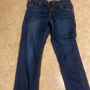 Levis 512 Slim Taper jeans - Snygga mörkblå Levis 512 Slim Taper jeans med klassisk femficksdesign och gul kontrastsöm. Perfekta för en stilren look med en smalare passform som smalnar av vid anklarna.