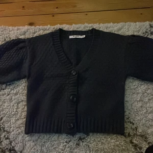 Marinblå kofta från NA-KD - Säljer en marinblå kofta från NA-KD med knappar framtill. Koftan är croppad och har en v-ringad design. Perfekt för en stilren look. Använd en gång.