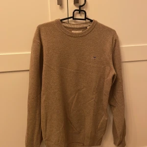 Beige tröja från Gant - Small - Säljer en stilren beige tröja från Gant. Tröjan har en liten logga på bröstet och är tillverkad i ett mjukt material. 