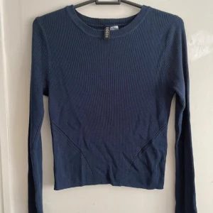 Blå ribbad tröja från H&M - Säljer en snygg blå ribbad tröja från H&M. Tröjan har långa ärmar och en rund halsringning. Perfekt för en stilren look. Passar bra till både jeans och kjol.