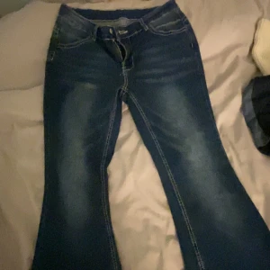 Blå bootcut jeans - Snygga blå bootcut jeans med klassisk femficksdesign och ljusa slitningar. Perfekta för en avslappnad stil. De har en bekväm passform och är tillverkade i ett slitstarkt denimtyg.