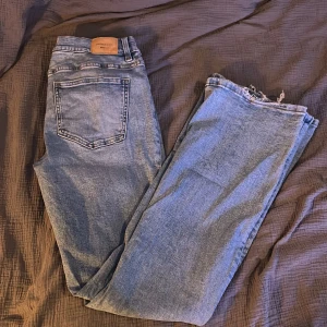 Blå jeans från Gina tricot - Säljer ett par blå jeans från Gina tricot. De är en low bootcut med slitna kanter vid bensluten. De har ett fint ribbat mönster på byxan vilket enligt mig är väldigt fint🩷