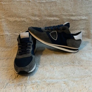 Blå och grå sneakers från Philippe Model - Snygga sneakers i blått och grått från Philippe Model. Skorna har en stilren design med snörning och en vit sula. Perfekta för en avslappnad stil.