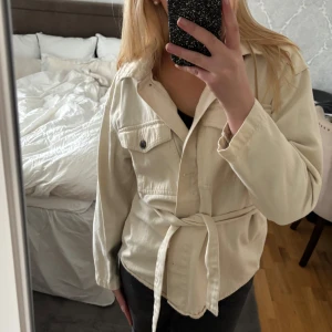 Beige jacka - Säljer en beige/ off-white jacka med knytband i midjan. Jättefin vårjacka