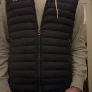 Svart dunväst från Colmar - Säljer en snygg svart dunväst från Colmar. Västen har en dragkedja framtill och två praktiska fickor med dragkedjor. Perfekt för lager-på-lager under kyliga dagar. 🖤