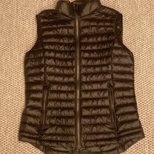 Svart dunväst från Everest - Snygg svart dunväst med dragkedja framtill. Perfekt för lager-på-lager under kyliga dagar. Det är en snygg dunväst med svart färg och puffar. Inga skador är fram varandra👍.