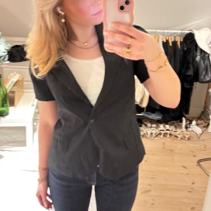 Svart kavajväst - Snygg svart kavajväst med korta ärmar och knäppning fram. Lite puffiga axlar. Det är egentligen en L men passar S-L beroende på hur man vill att den ska sitta🥰