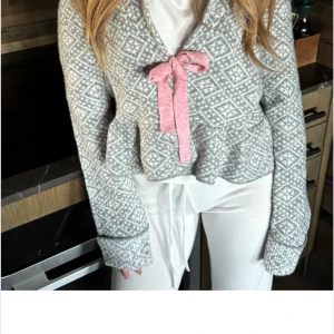 Grå mönstrad kofta med rosa rosett - Säljer en söt grå kofta från Nelly som liknar odd molly. Aldrig använd!