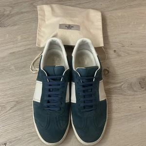 Valentino Flycrew - Snygga Valentino flycrew sneakers i blå mocka med vita detaljer. Skorna har en stilren design med snörning och små nitar på sulan. Perfekta för en trendig look. Saknar dock tyvärr 3 nitar på ena skon och 4 på den andra men inget man tänker på eller ser på avstånd. Säljer de då jag är sugen på antingen en ny färg eller ett par andra skor. 