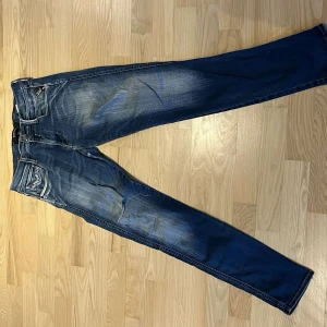 Replay anbass jeans - Snygga blå jeans med en klassisk femficksdesign och lätt slitna detaljer. Byxorna har en dragkedja och knapp framtill. Perfekta för en avslappnad stil. W28 L32,kontakta oss vid frågor🤝