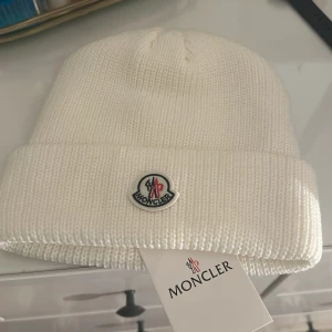 Vit stickad mössa från Moncler - Snygg vit stickad mössa från Moncler som jag fick i present men inte kom till användning.