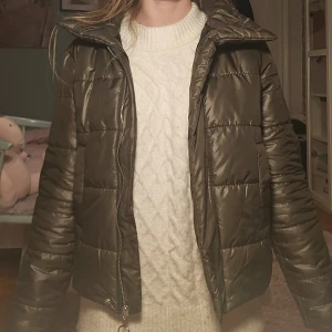 Olivgrön dunjacka - Säljer en olivgrön dunjacka med dragkedja och knappar. Jackan har en hög krage och långa ärmar, perfekt för kyliga dagar. Jackan är i storlek s men är ganska liten i storleken. Den är dessutom lite grönare i verkligheten jämfört med bilden