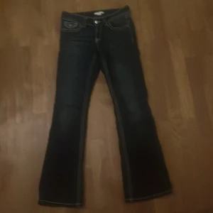 Mörkblå bootcut jeans - Snygga mörkblå bootcut jeans med klassisk femficksdesign och kontrastsömmar. Perfekta för en avslappnad stil. De har en knapp och dragkedja framtill.