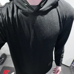 Svart tyg tröja  - Säljer en stilren svart hoodie med långa ärmar och justerbar huva. Perfekt för en avslappnad look. Passar bra till både jeans och träningsbyxor.